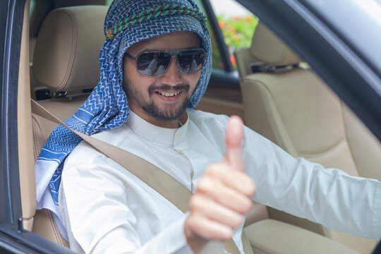 Successful Arab Man in Keffiyeh Giving Thumbs Up while Driving Car