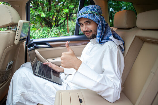 Arab Businessman Using Laptop with Thumbs Up in Luxury Car