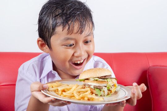 Excited Boy Holding Plate with Large Burger and French Fries