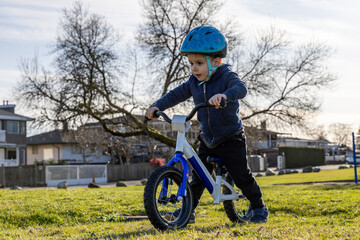 Obraz premium Young Boy Learning To Ride A Bike With Helmet In A Park In Burnaby Vancouver BC
