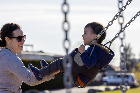 Mother Pushing Son On Swing At Playground In Burnaby Vancouver BC Canada, Happy Family Moment
