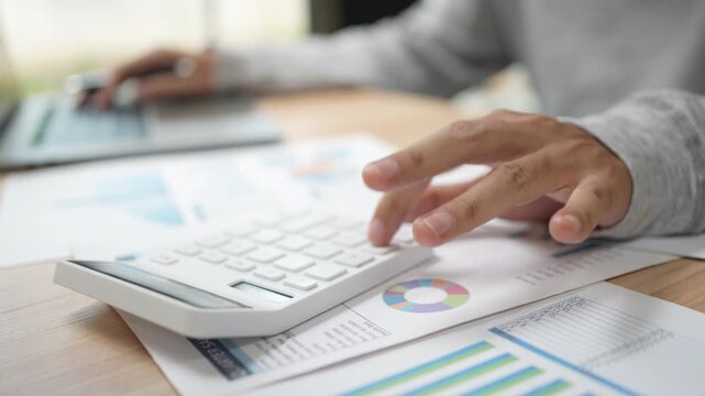 Financial planning and budgeting are essential for individuals and businesses. This shows a person using a calculator and analyzing various business reports and charts on a desk.