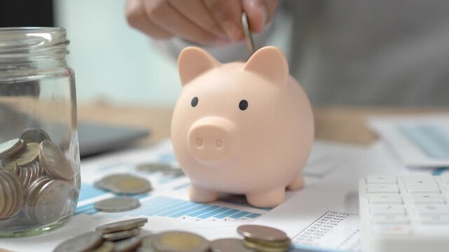 Hand putting coins into piggy bank for savings and budget planning concept.