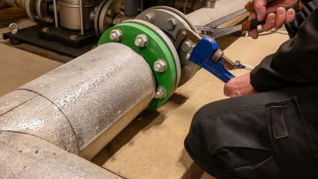 Specialist plumbing and pressurisation engineer working on a high rise industrial water booster set. Pump service engineer carrying out essential planned maintenance.