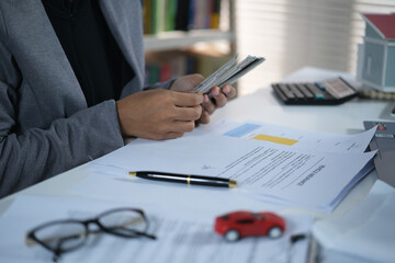 Fototapeta premium Bussines woman counts dollar bills with a miniature red car on his desk, The concept of installment payments, rent, buying and selling, insurance and vehicle tax. 