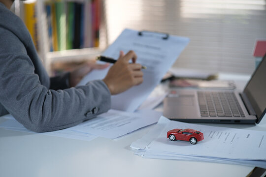 A car sales office and a salesperson negotiating a car title. A salesperson guides a customer sitting at a table. Car business. Car sales. Selling and leasing cars with insurance.
