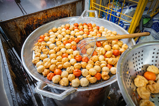 Spicy Thai meatballs cooking in a pot of hot oil at a street food stall in Si Lom, Bangkok, Thailand