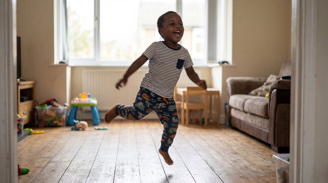 Children's Day toddler dancing laughing in living room indoors for celebration greeting cards social media joyful childhood movement music marketing promotional content