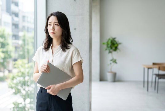 ノートPCを持ち悩む日本人女性 Generative AI