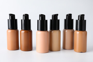 Obraz premium Bottles of skin foundations in different shades on light grey background, closeup