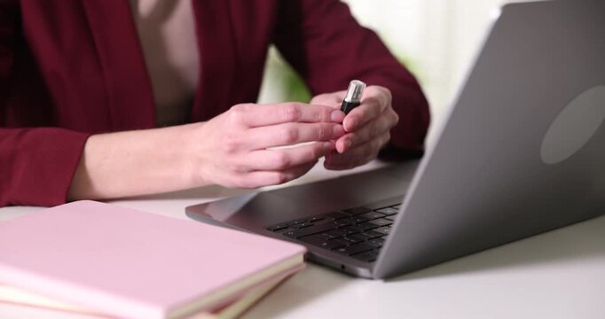 Woman working on laptop and taking USB flash drive at desk, closeup