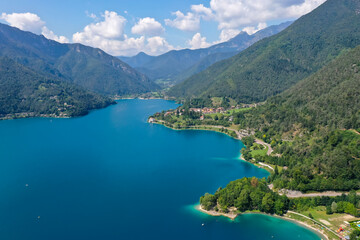 Fototapeta premium Aerial view of Lago di Ledro in northern Italy, surrounded by green mountains on a partly cloudy summer day. 