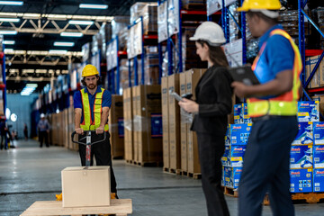 Obraz premium A diverse logistics team utilizing digital tablets, a walkie-talkie, and a hand pallet jack to verify cargo stock distribution parameters within a warehouse.