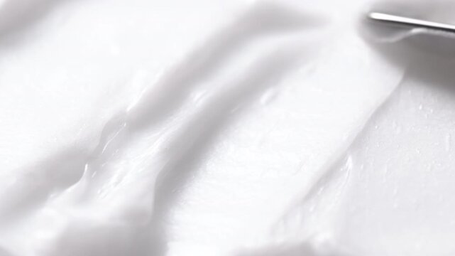 Close-up of white cosmetic cream texture being smoothed with a spatula
