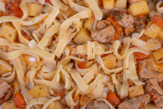Close crop homemade lagman rich in noodles, cubed vegetables and diced meat, steamhazy and inviting cozy comfortfood texture with visible seasoning and warmth