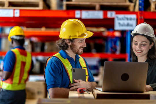 Collaborative logistics team reviewing stock availability in a large warehouse. Industrial specialist pointing at high shelves with a manager for inventory audit and strategic planning.