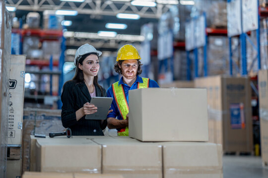 A logistics manager using a tablet to coordinate stock distribution parameters and verify cargo carton quantities with warehouse team operators.