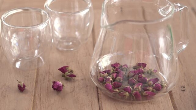 Close-up of hot organic rose tea being poured from a teapot into a clear glass cup, healthy herbal beverage for relaxation and wellness, rich in antioxidants and vitamins for healthy skin.