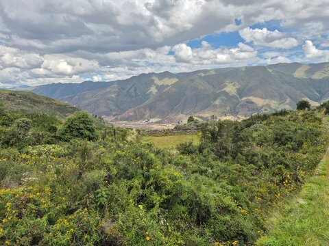 Large green valley with tiny town and mountain backdrop