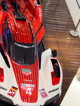 BELO HORIZONTE, MG, BRAZIL, MAY, 10, 2026 A red and white Porsche race car with sponsor logos on display in a showroom with a wooden floor
