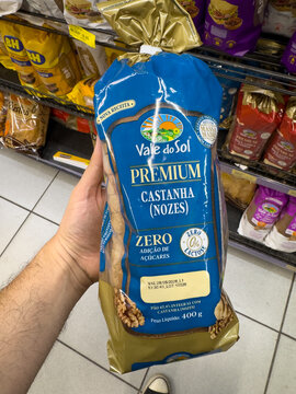 BELO HORIZONTE, MG, BRAZIL, MAY, 10, 2026 A hand holding a blue and gold bag of premium castanha nuts in a grocery store aisle