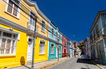 Fototapeta premium View of Templeman Street in between Cerro Concepcion and Cerro Alegre. Colorful historic houses line the steep cobblestone street under a deep blue sky