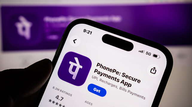 Closeup of a hand holding a smartphone displaying the phonepe mobile application on the apple app store screen