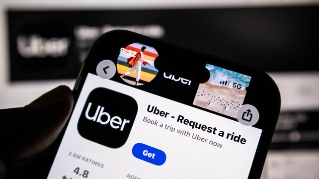 Closeup of a hand holding a smartphone displaying the uber app store page on the screen