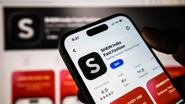 Closeup of a hand holding a smartphone displaying the shein india app store page on a screen