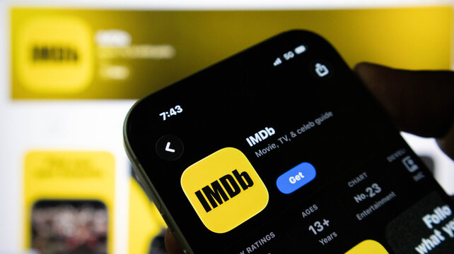 Closeup of a smartphone screen displaying the imdb app store page with the app icon, rating, and entertainment chart ranking visible