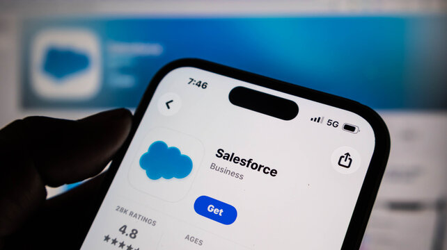 Closeup of a hand holding a smartphone displaying the salesforce app store page on the screen