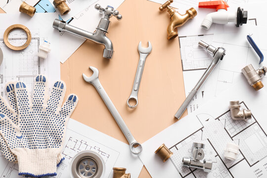 Frame made from set of plumber's items and house plans on beige background