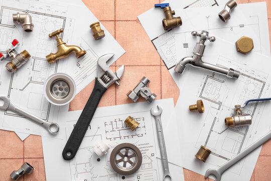 Set of plumber's items and house plans on beige tiled background