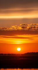 Obraz premium Vivid sunrise paints sky with orange, gold hues over hazy horizon