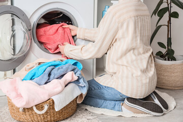 Naklejka premium Woman taking towel from washing machine in laundry room, back view