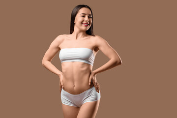 Obraz premium Happy young woman in stylish white underwear posing on beige background