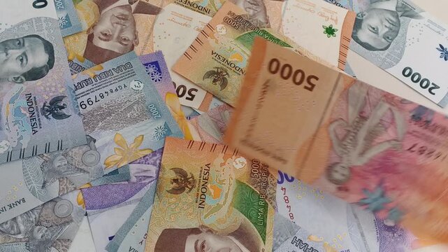 Real time footage of Indonesian rupiah banknotes falling onto white surface. Concept of finance, cash flow, economy, and money.