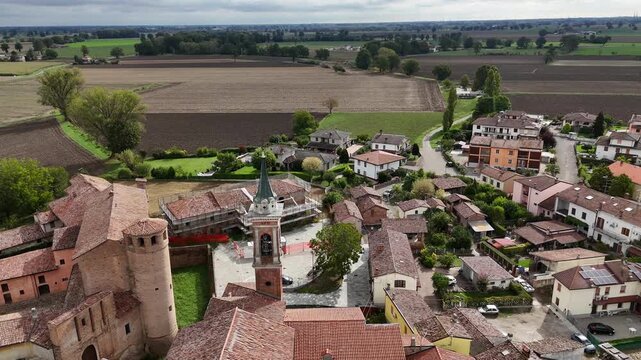 Calendasco Piacenza Emilia Romagna Italy with parish church tower, historic buildings and surrounding agricultural fields in Po Valley, drone descent shot