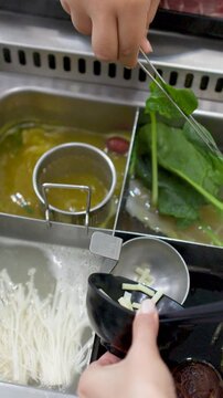 Adding Fresh Vegetables and Ingredients to a Boiling Hot Pot Soup