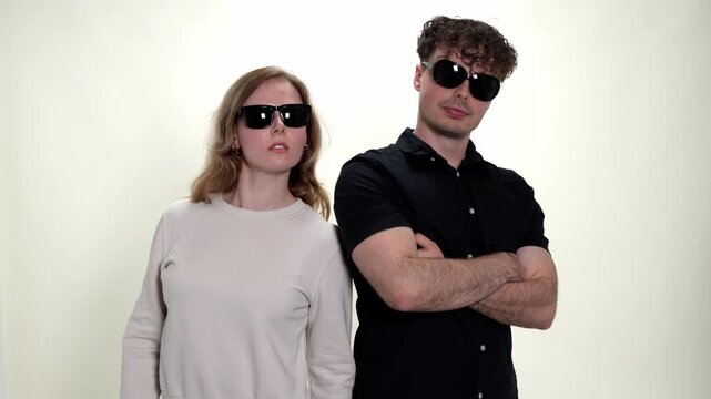 This depicts couple conflict and relationship issues, showing a young man and woman in sunglasses facing each other with serious expressions. The studio shot captures their tension and disagreement, m