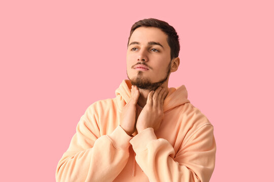 Young man with thyroid gland problem on pink background