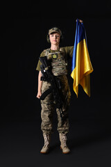 Obraz premium Young female soldier with flag of Ukraine on dark background