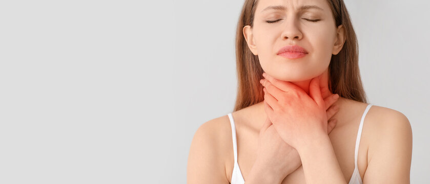 Young woman checking thyroid gland on grey background
