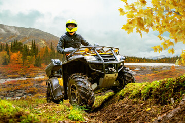 ATV rider drives off road through autumn wilderness near river and mountains. © Grispb