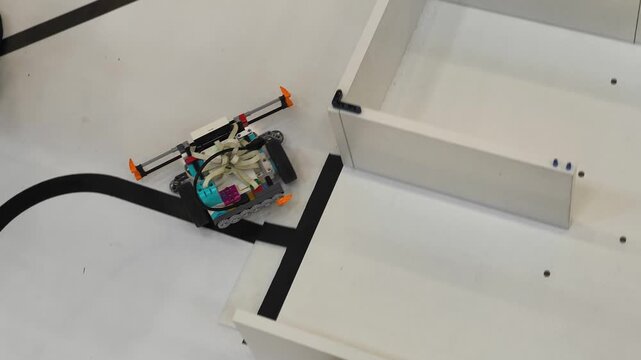 Top view - the robot moves inside the maze on the training field for competitions in robotics, STEM, programming, engineering training.
