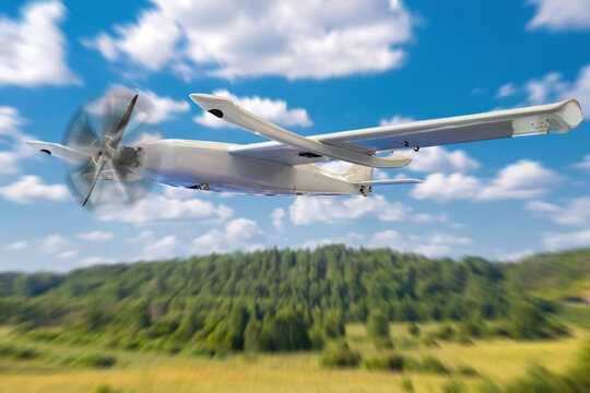 Aviation, Drone technology. Fixed-wing unmanned aircraft flies above rural landscape during test flight, aerial monitoring, mapping and surveillance work.