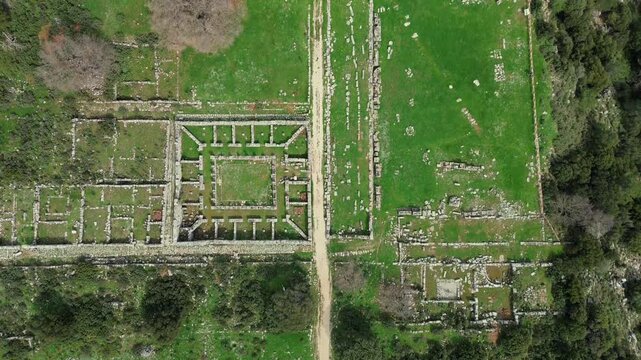 Stunning 4K drone bird's eye view over ancient Kassope ruins. Abstract geometric landscape of ancient Greek city street grid, agora foundations and stone walls in Epirus.