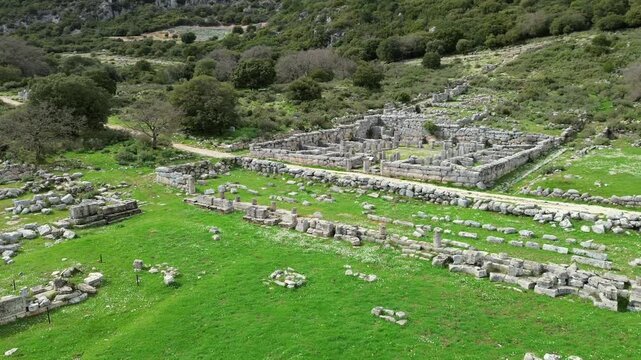 Cinematic 4K drone panoramic shot over the ancient stone ruins of Kassope in Epirus, Greece. Featuring ancient agora walls, street layouts and historic foundations in spring.