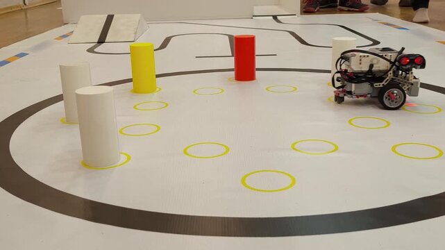 Low angle - the robot works with colored cylinders on a competitive field in robotics, STEM, programming, engineering training.
