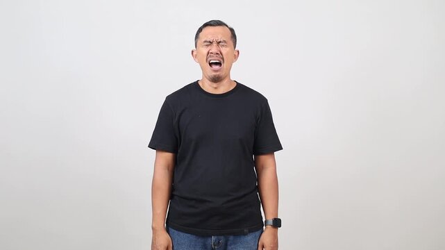 Frustrated Asian man crying and panicking in despair, having problems, standing upset on a white background.